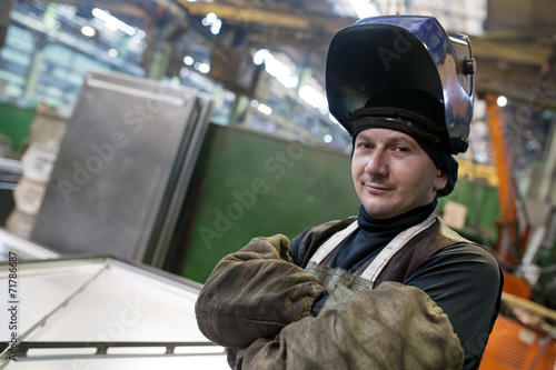 Caucasian welder worker at factory workshop background
