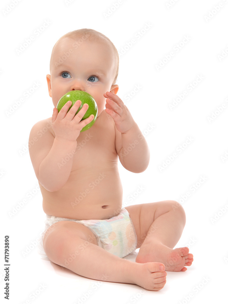Happy child baby boy sitting in diaper and eating green apple Happy child baby boy sitting in diaper and eating green apple