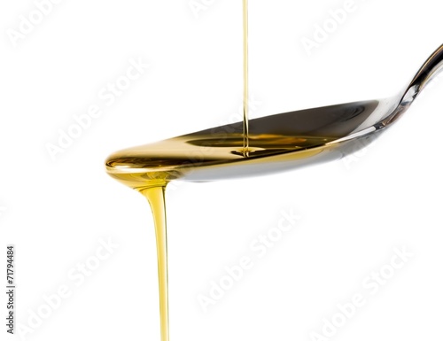 Extra virgin olive oil pouring over a spoon on white background
