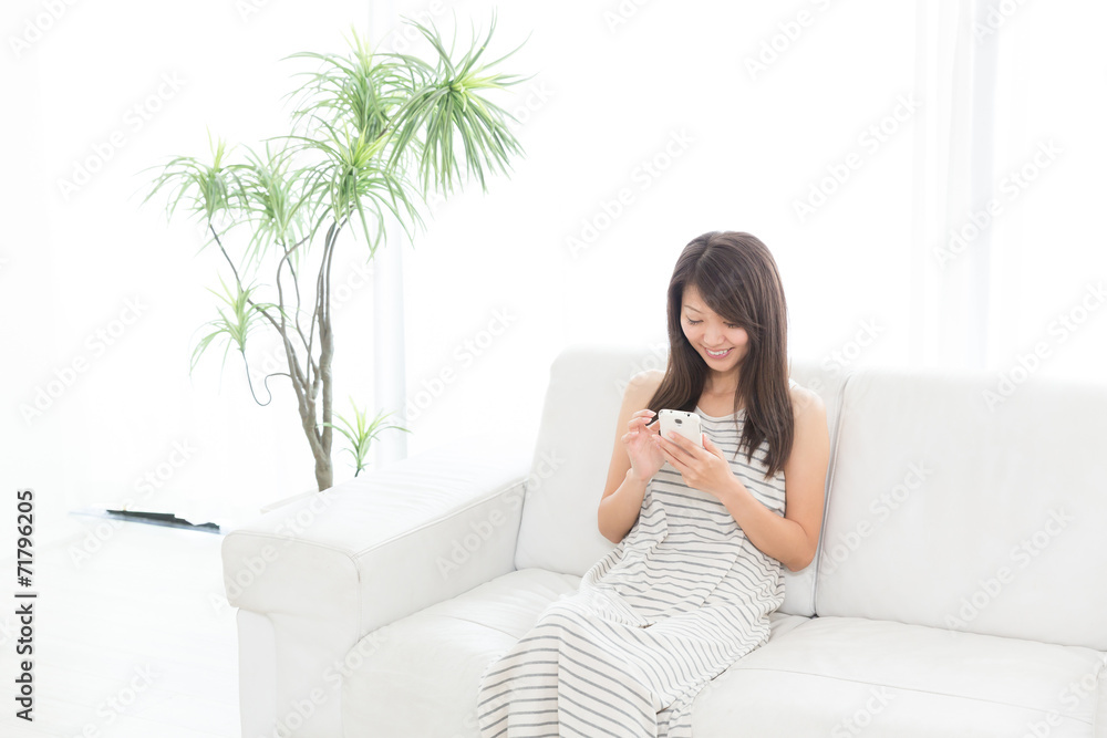 部屋でスマートフォンを見る女性