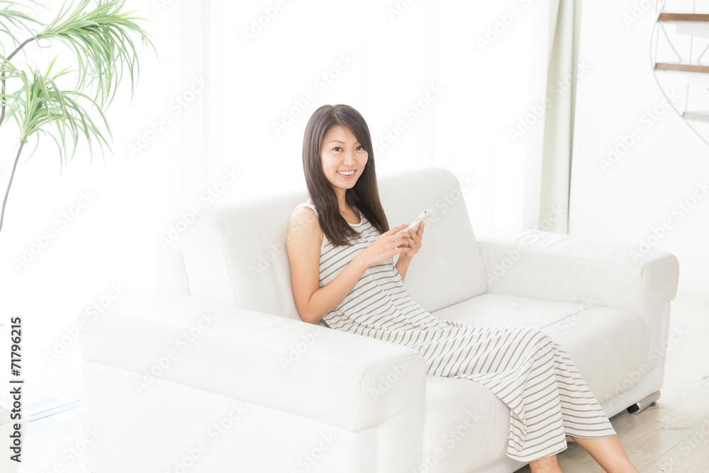 部屋でスマートフォンを見る女性 部屋でスマートフォンを見る女性