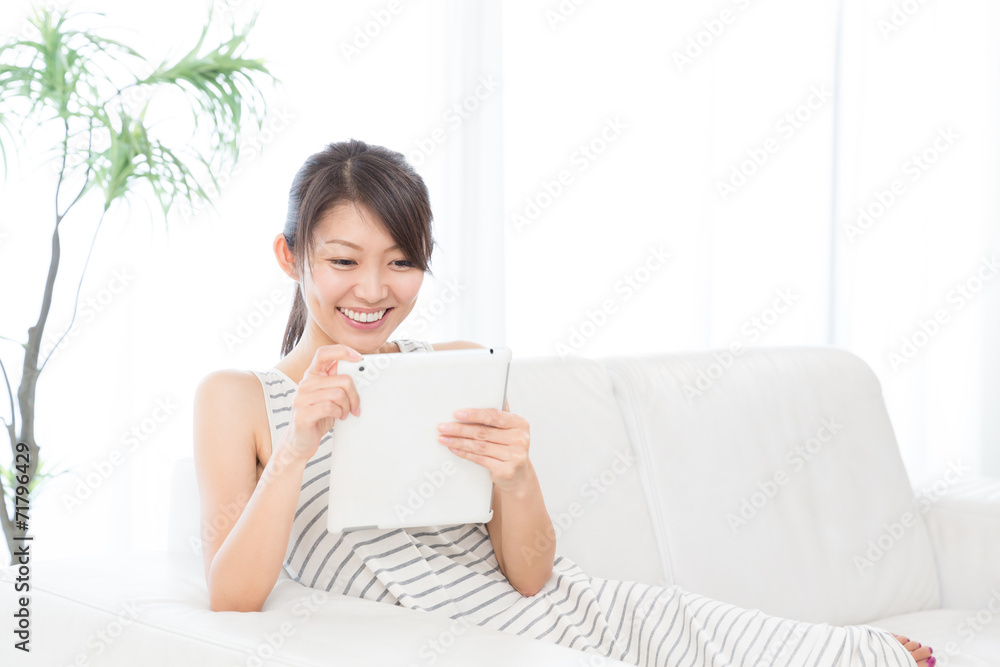 部屋でタブレットを見る女性