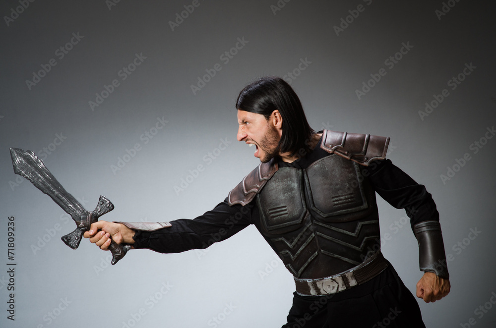 Angry knight with sword against dark background Angry knight with sword against dark background