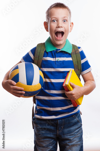 Happy schoolboy with backpack, ball and books 