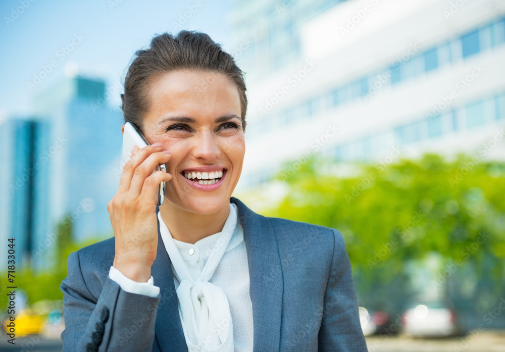 Smiling business woman talking cell phone in office district Smiling business woman talking cell phone in office district