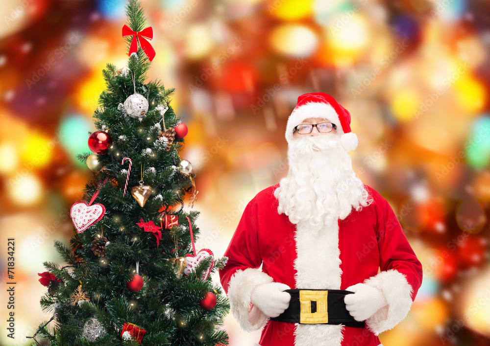 man in costume of santa claus with christmas tree man in costume of santa claus with christmas tree