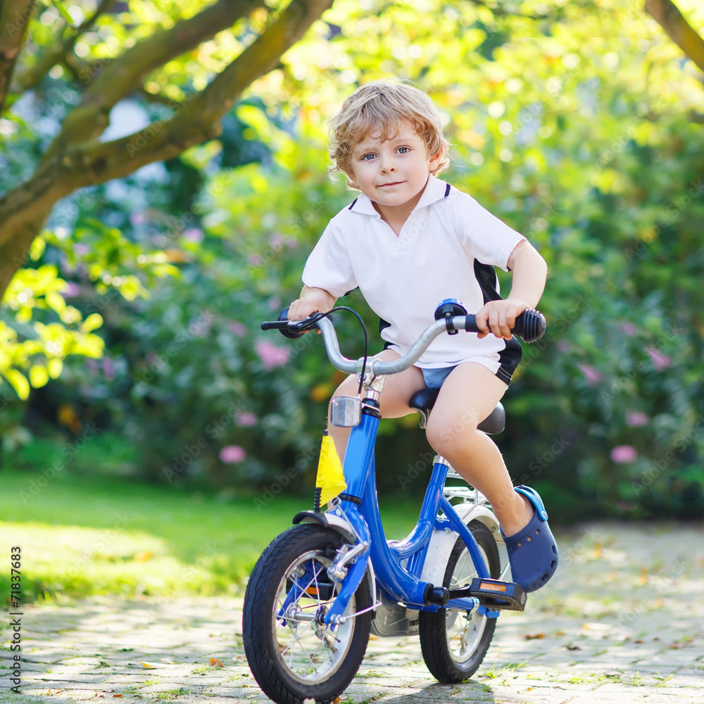 Adorable child having fun with riding his first bicycle Adorable child having fun with riding his first bicycle