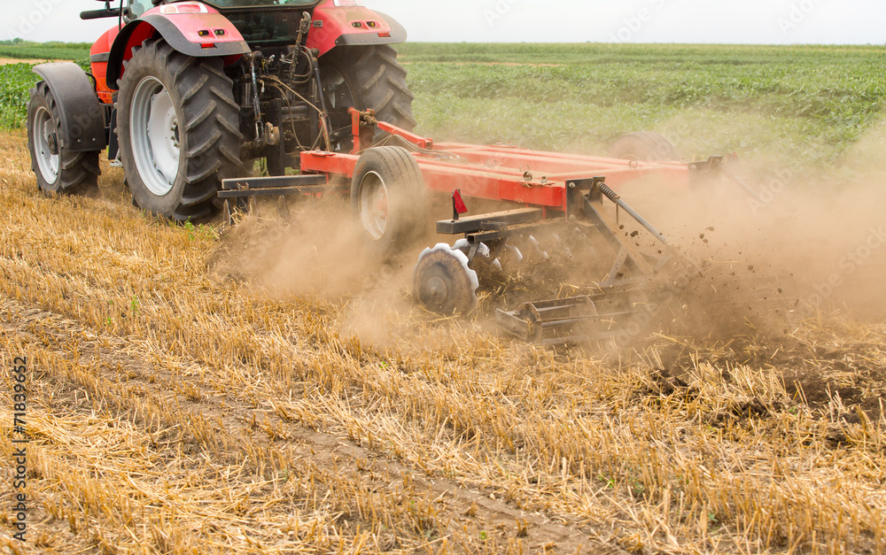 Obraz premium Tractor cultivating wheat stubble field, crop residue.