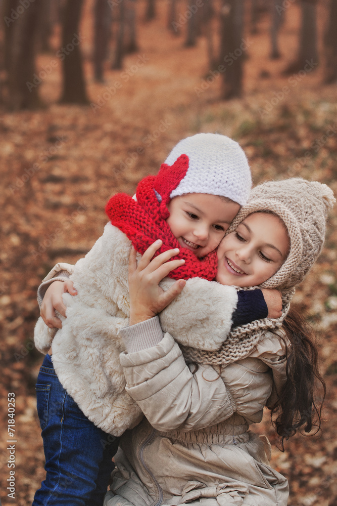 Obraz premium Cute Girl hugging her baby sister in a beautiful winter park