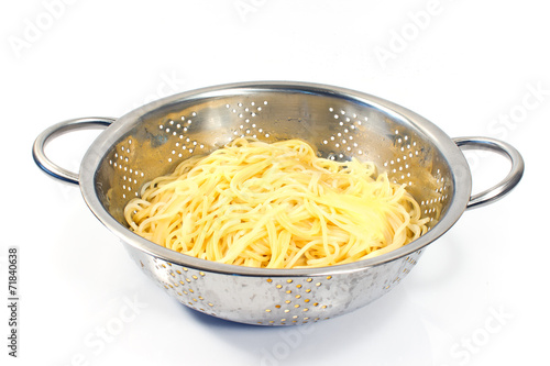 Slika na platnu Fresh cooked spaghetti in stainless strainer isolated on white