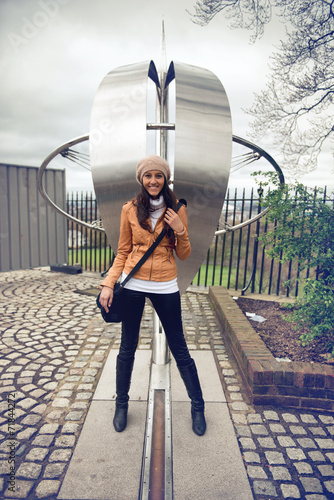 Smiling woman straddling the prime meridian line photo