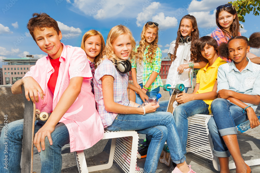 Obraz premium Group of kids sit on white chairs with skateboards