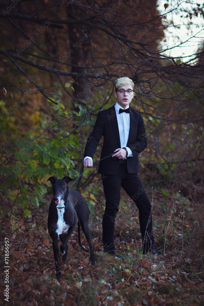 Young attractive man in suit and tie with a greyhound dog in aut