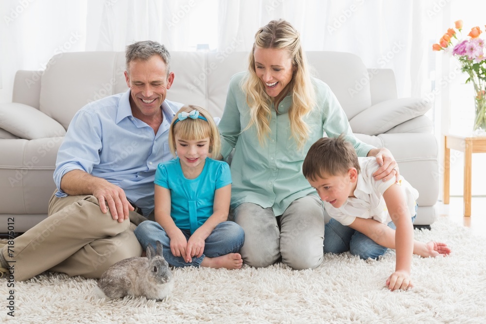 Smiling family with their rabbit on the rug