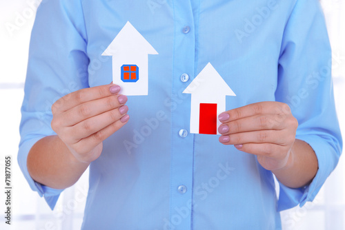 Woman hands holding paper houses on light background