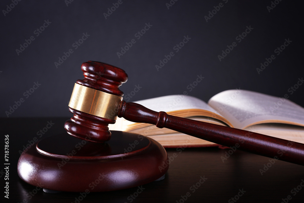 Judge's gavel and open book on dark grey background