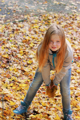 Girl throwing autumn leaves in the park