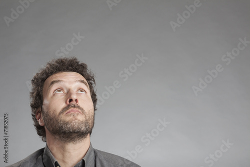 Mann in grauem Hemd schaut nach oben photo