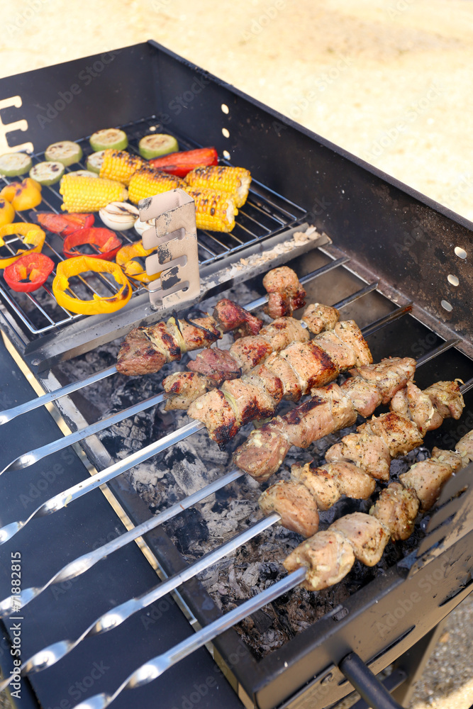 Skewers and vegetables on barbecue grill, close-up