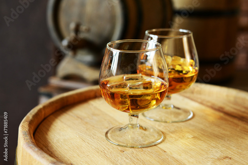 Glasses of brandy in cellar with old barrels photo