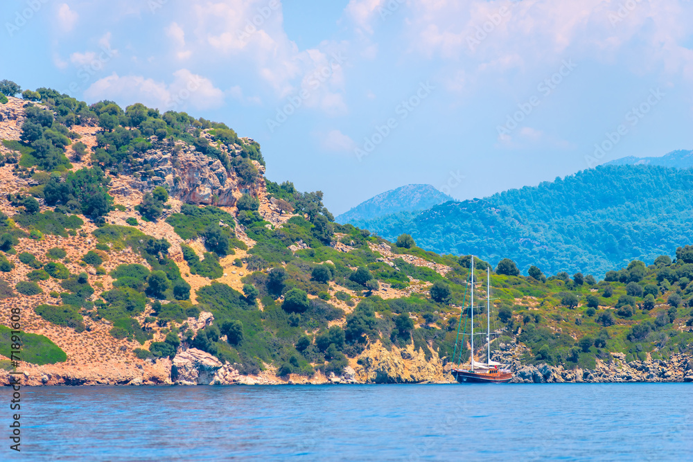 Fototapeta premium lonely sailing yacht moored to a rocky shore
