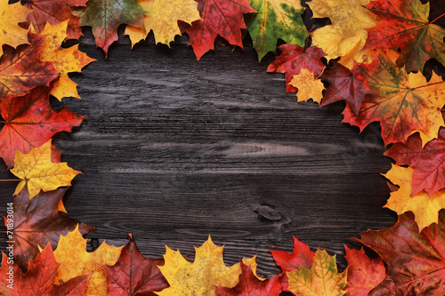 Frame with autumn leaves on a wooden background