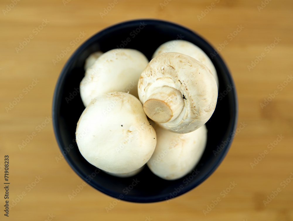 White mushrooms in black bowl on wooden board White mushrooms in black bowl on wooden board