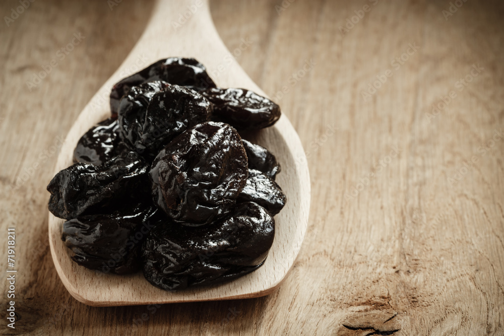 dried plums prunes on wooden spoon dried plums prunes on wooden spoon