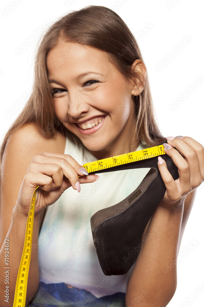 smiling young woman measured her heels with a measuring tape smiling young woman measured her heels with a measuring tape
