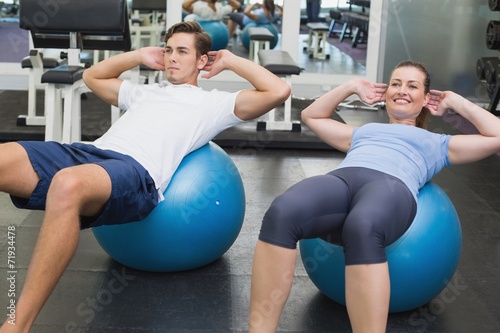 Couple doing sit ups on exercise balls