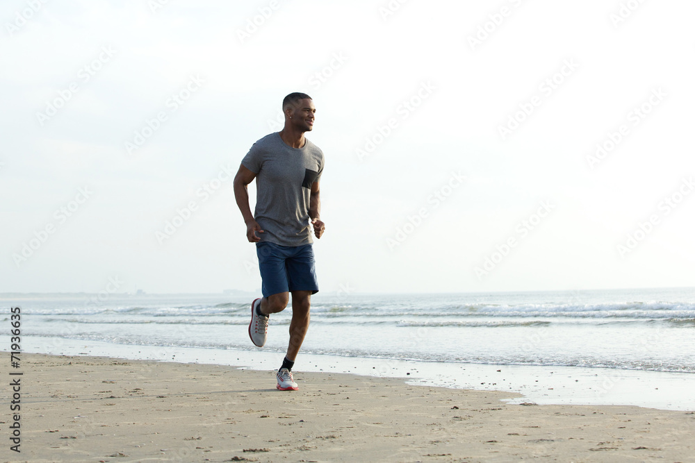 Young african man jogging at the beach