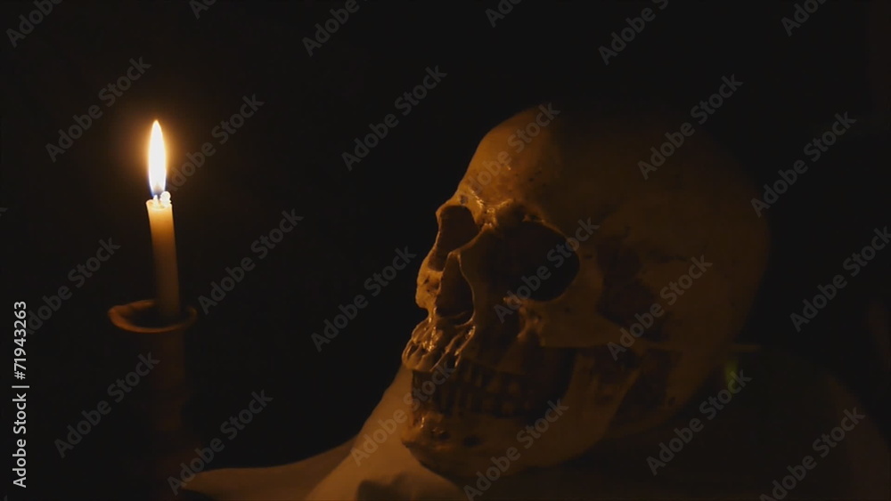 Halloween image with human skull and burning candle Halloween image with human skull and burning candle