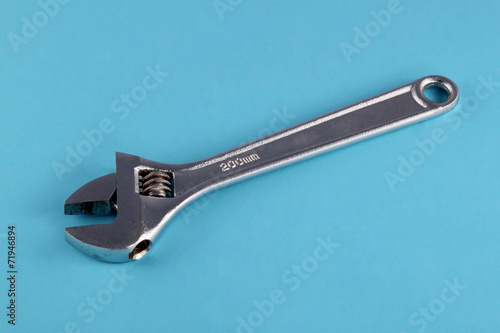 Adjustable wrench or spanner on a blue background.
