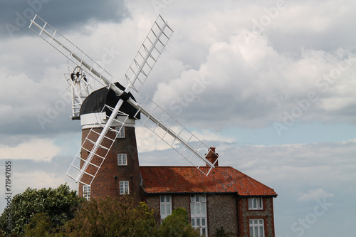 A Traditional Windmill Adjacent to a Brick House.