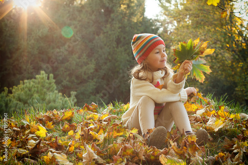 Cute child playing with autumn leaves