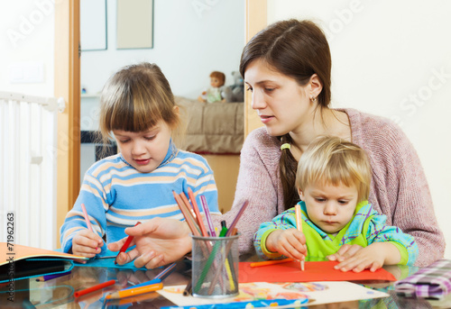 Mother and two children together with pencils