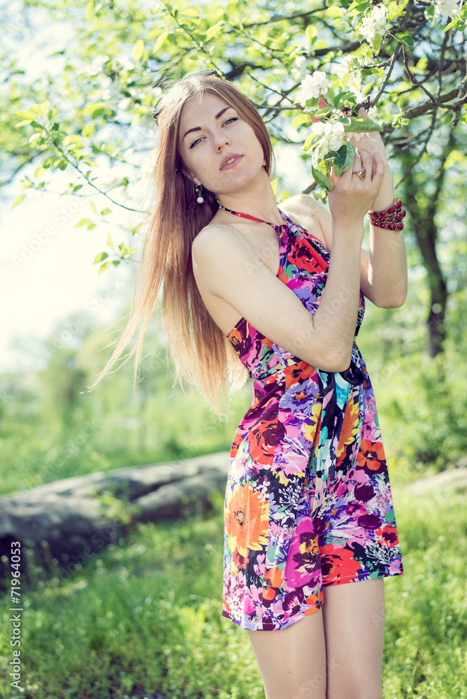 blond young woman standing under blooming tree blond young woman standing under blooming tree