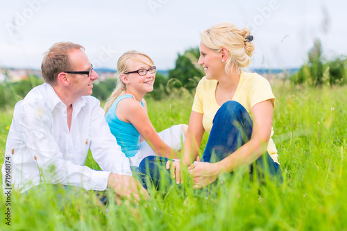 Family sitting on grass of lawn or field