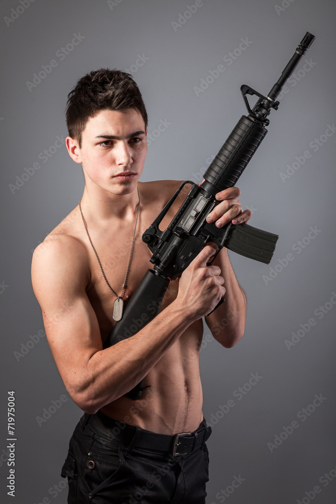 Handsome bare-chested soldier is holding a rifle Handsome bare-chested soldier is holding a rifle