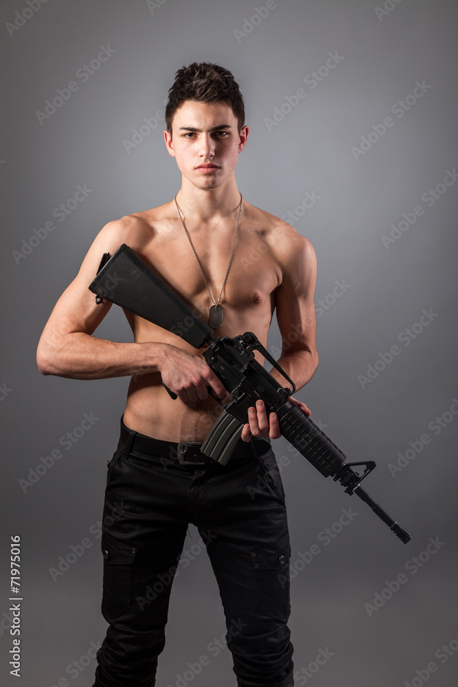 Handsome bare-chested soldier is holding a rifle Handsome bare-chested soldier is holding a rifle