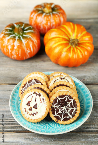 Tasty Halloween cookies on plate, on wooden table