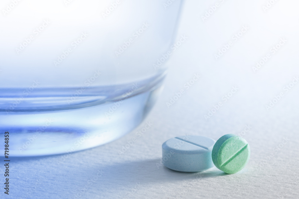 Glass of water and pill on white background,with light blue. Glass of water and pill on white background,with light blue.