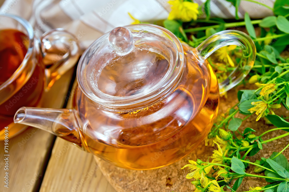 Herbal tea from tutsan in glass teapot with cup on board Herbal tea from tutsan in glass teapot with cup on board