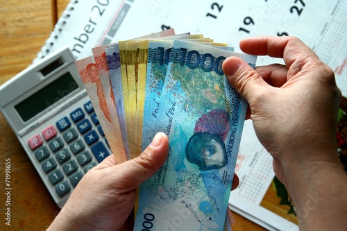 Hands holding Money Bills and a calculator and a calendar