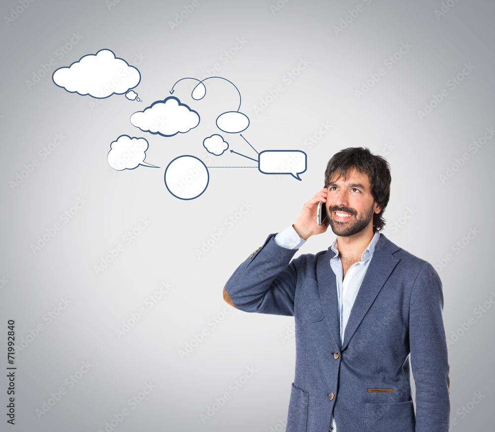 Handsome man talking to mobile over grey background Handsome man talking to mobile over grey background