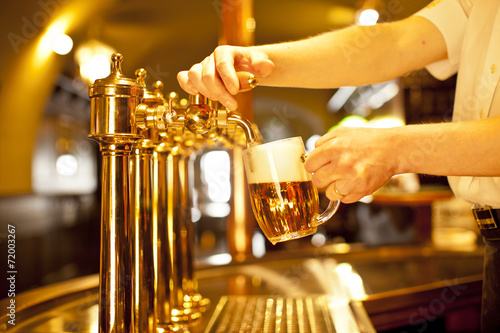 Fotografie, Obraz Zlaté pivo v ruce a pivních kohoutů