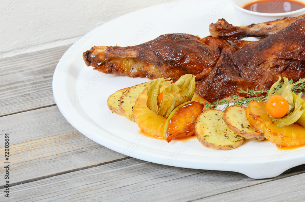 The baked half of duck with a potato, apples and pineapple The baked half of duck with a potato, apples and pineapple