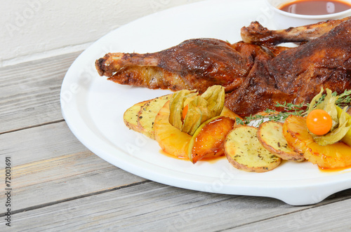 The baked half of duck with a potato, apples and pineapple