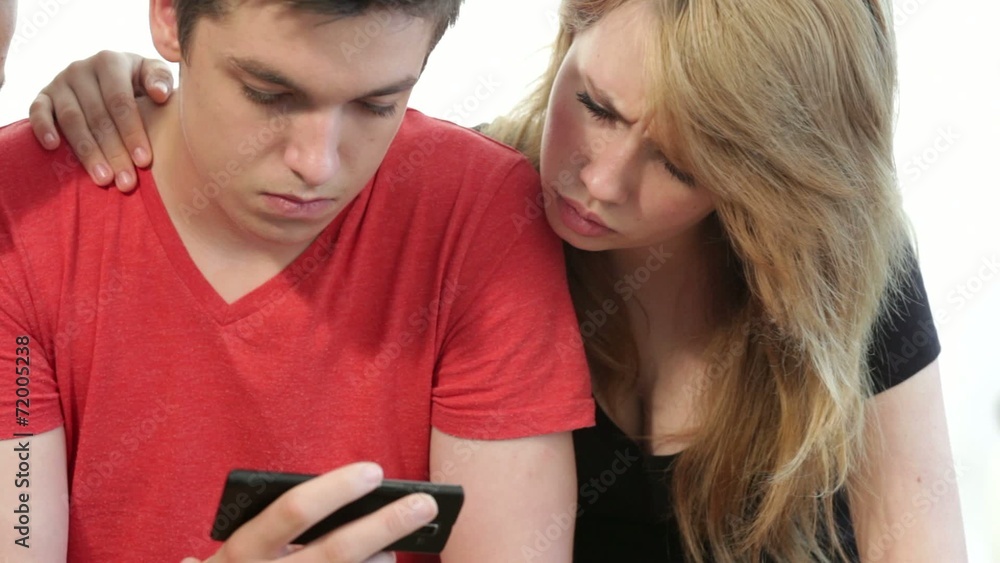 Couple of teenagers looking at a smart phone Couple of teenagers looking at a smart phone