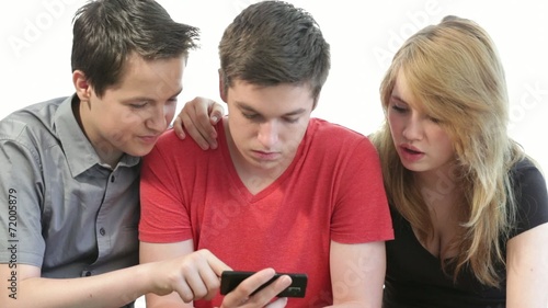 Small group of three teenagers looking at a smart phone screen, 